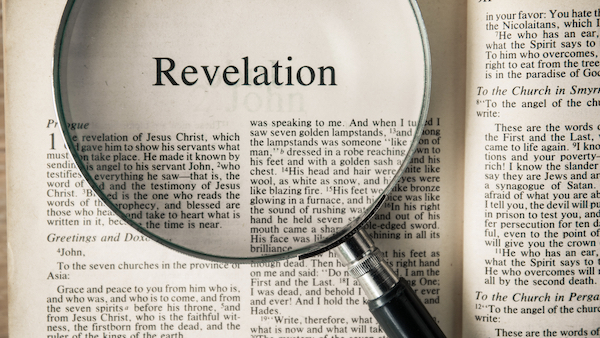 open bible to the book of revelation with a magnifying glass on top