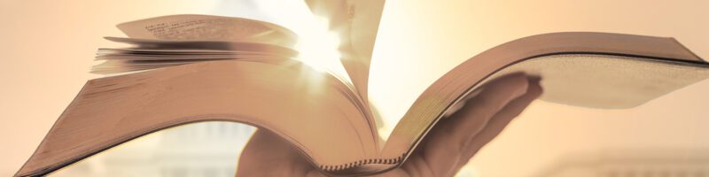 a hand holding up a bible in front of the united states capitol building